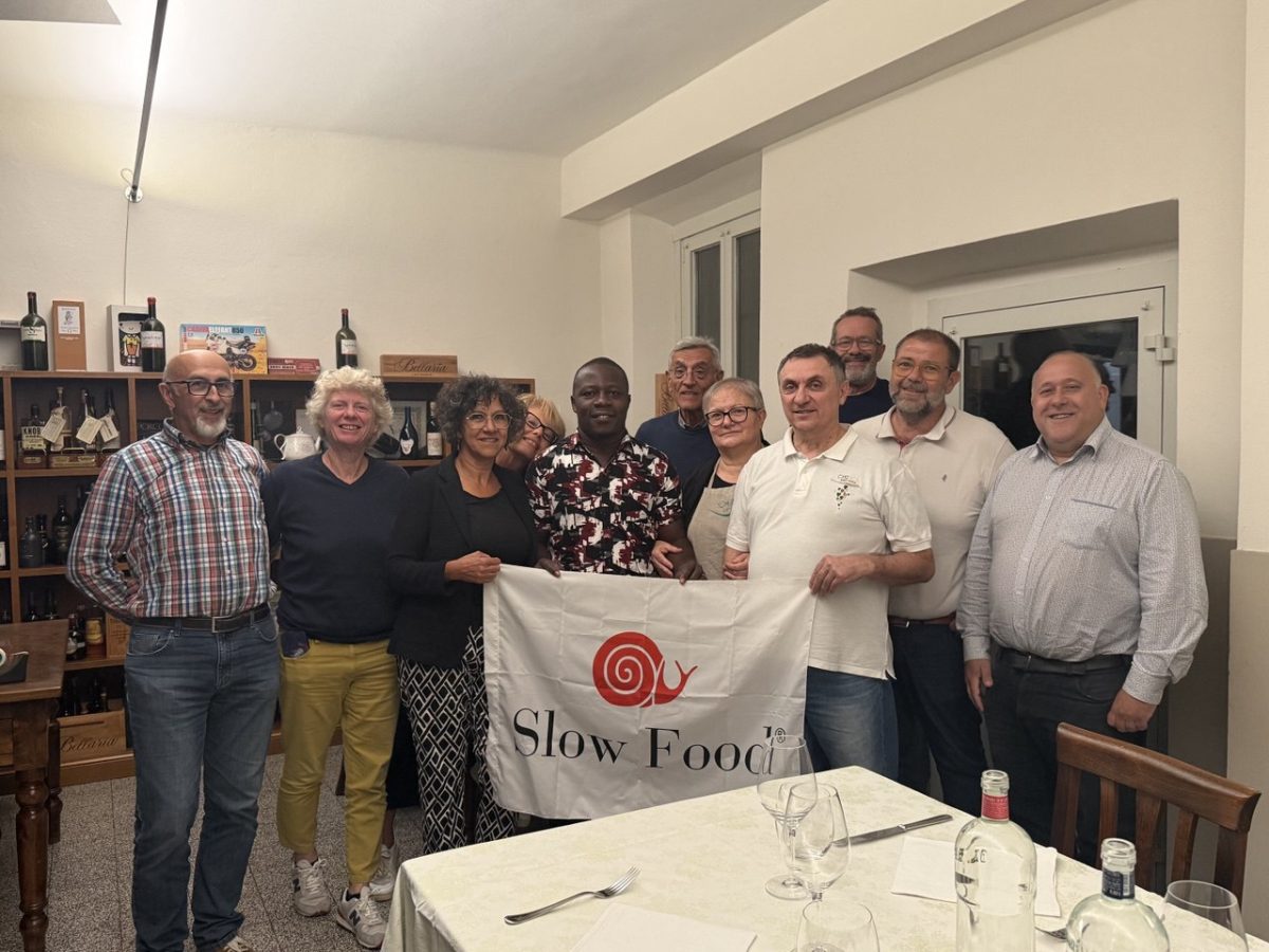La delegazione di Slow Food, inclusi il presidente Edward Mukiibi e il prof. Francesco Sottile, a cena da Chez Nadi con la bandiera di Slow Food